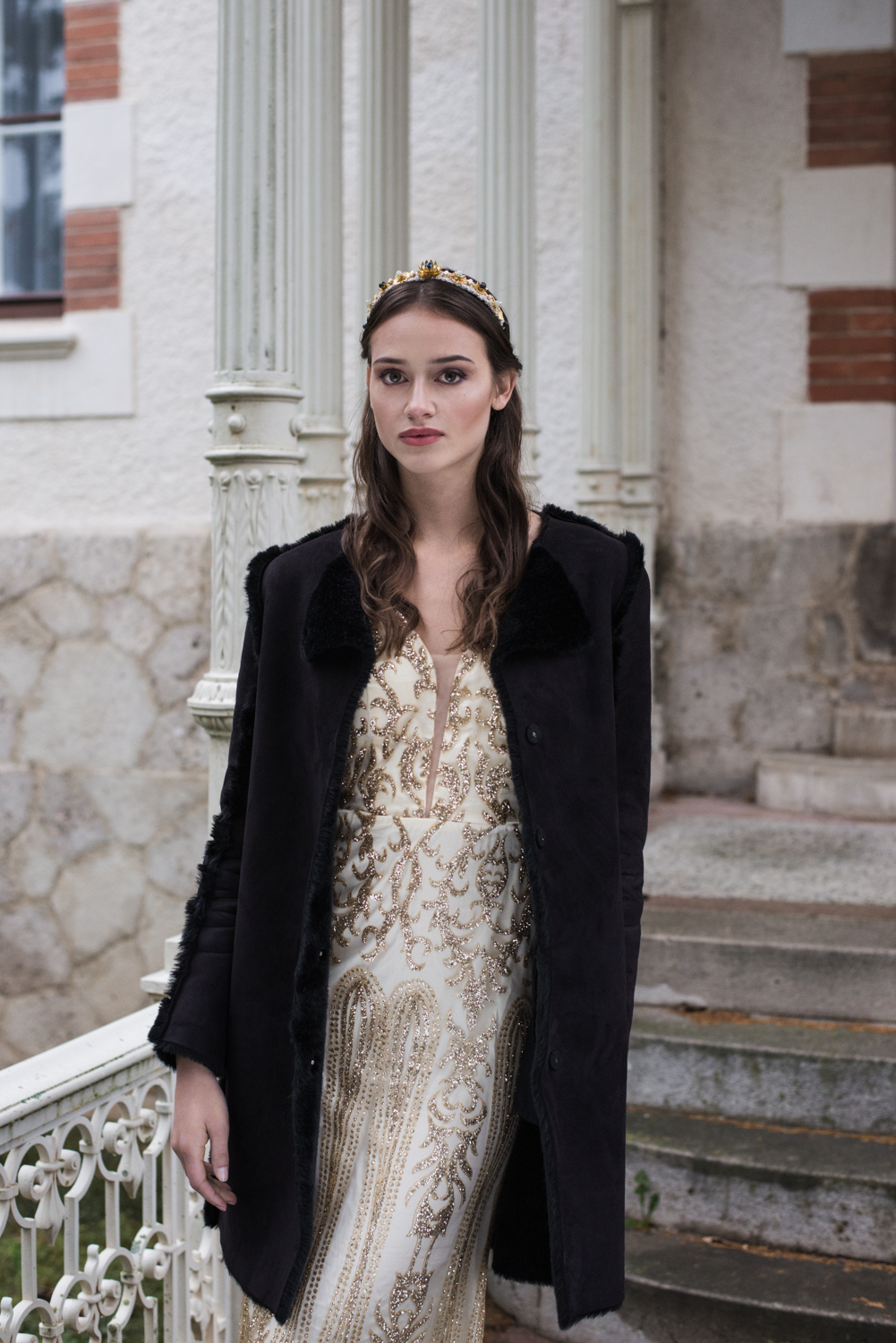 woman in golden dress wearing black coat at her villa